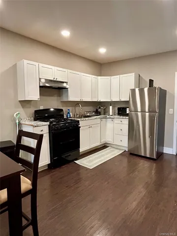 a kitchen with stainless steel appliances a stove a sink a refrigerator and chairs