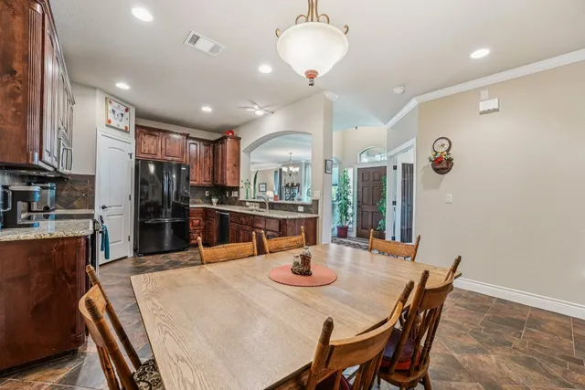 a kitchen with stainless steel appliances kitchen island granite countertop a dining table chairs and refrigerator