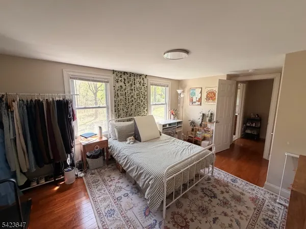 a bedroom with a bed a dresser and a large mirror next to a window
