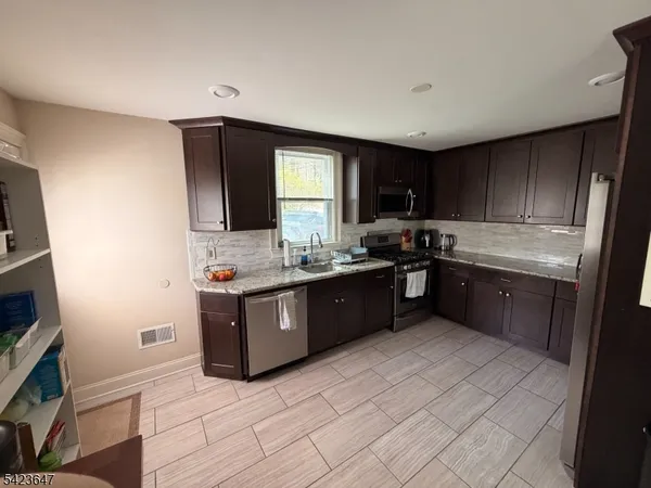 a kitchen with stainless steel appliances kitchen island granite countertop a stove a sink and a refrigerator
