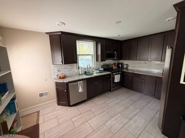 a large kitchen with stainless steel appliances granite countertop a sink counter space cabinets and a large window