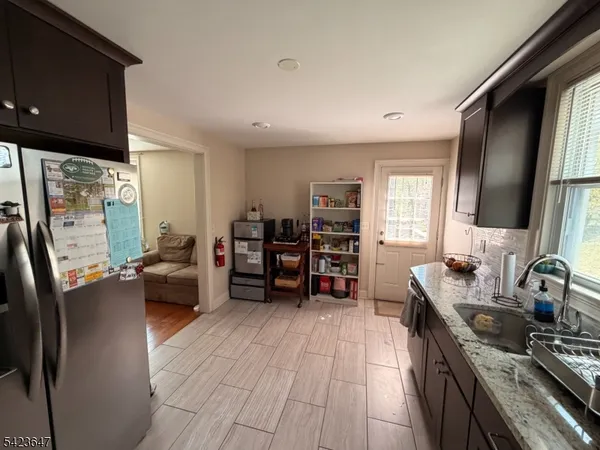 a kitchen with stainless steel appliances a stove top oven a sink a dining table and chairs