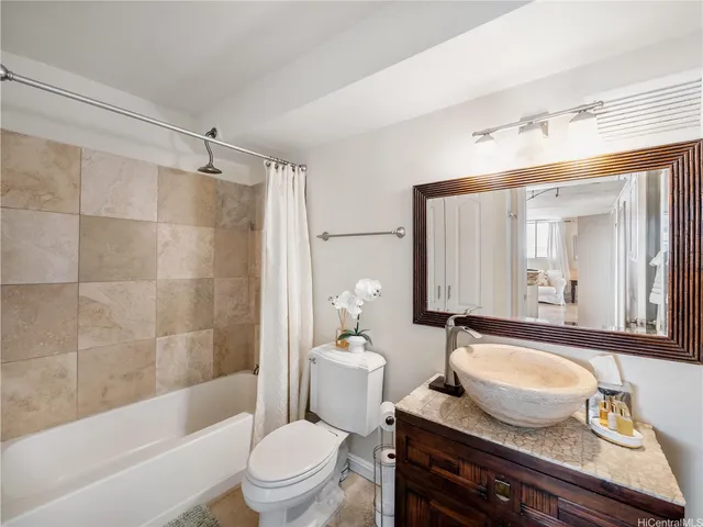 a bathroom with a granite countertop sink toilet a mirror and bathtub