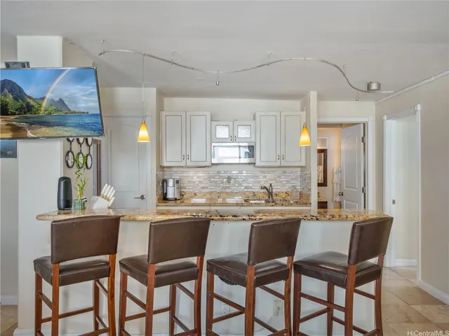 a kitchen with stainless steel appliances kitchen island granite countertop a dining table chairs and a refrigerator