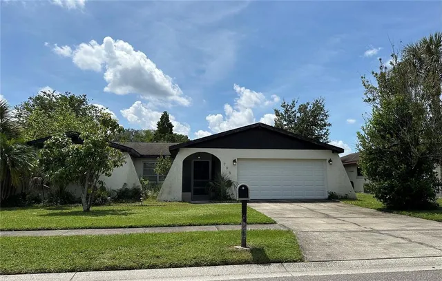 a front view of a house with a garden and trees