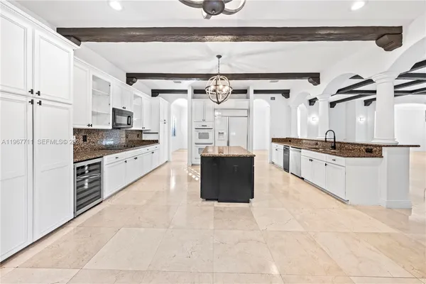 a large kitchen with stainless steel appliances granite countertop a stove a refrigerator and a cabinets with wooden floor