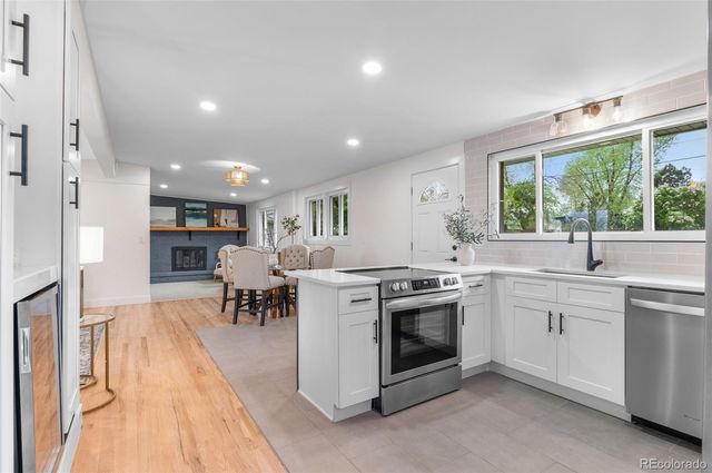 a open kitchen with kitchen island a stove a sink a dining table and chairs with wooden floor