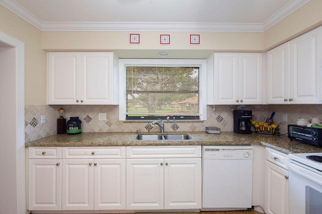4600 Wildwood Tree Lane, Unit A Boynton Beach, FL 33436 - Photo 19 of 30 a kitchen with granite countertop white cabinets and white appliances