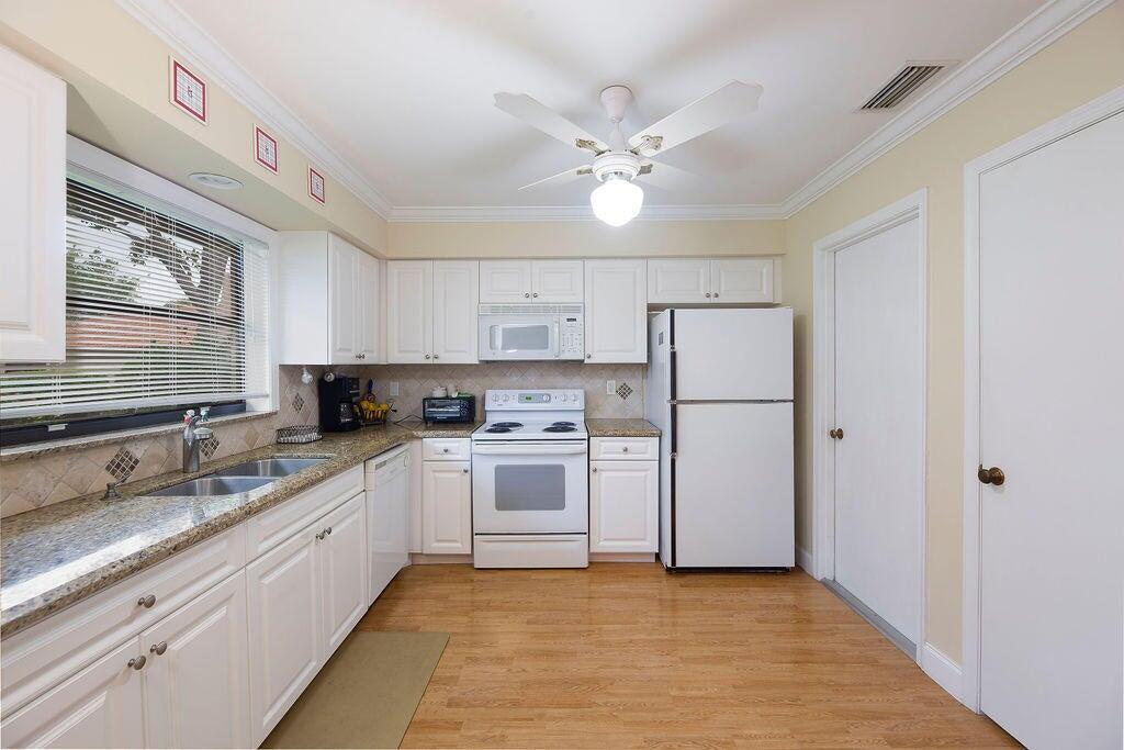 4600 Wildwood Tree Lane, Unit A Boynton Beach, FL 33436 - Photo 20 of 30 a kitchen with white cabinets and white appliances