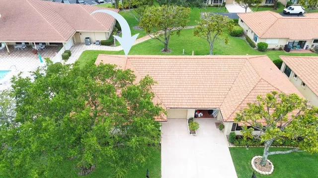 an aerial view of a house with swimming pool and large trees