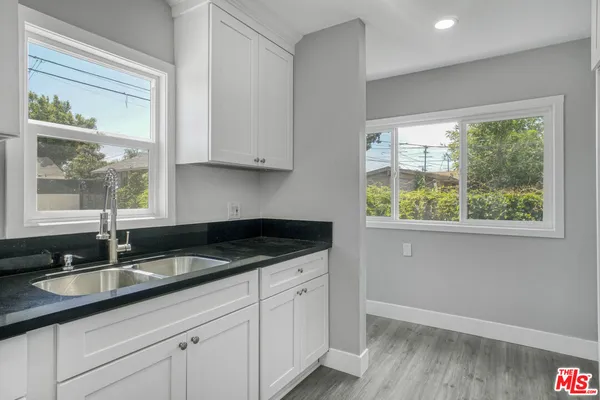 a kitchen with granite countertop a sink and a white wooden cabinets