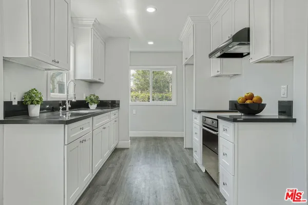 a kitchen with stainless steel appliances a stove a sink and white cabinets