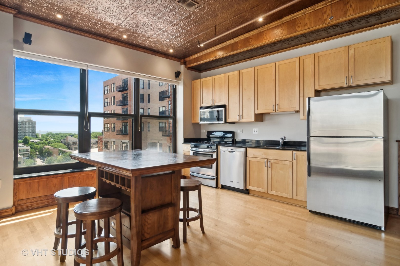 1503 South State Street, Unit 813 Chicago, IL 60605 - Photo 5 of 11 a kitchen with stainless steel appliances granite countertop a stove a refrigerator a sink a dining table and chairs with wooden floor