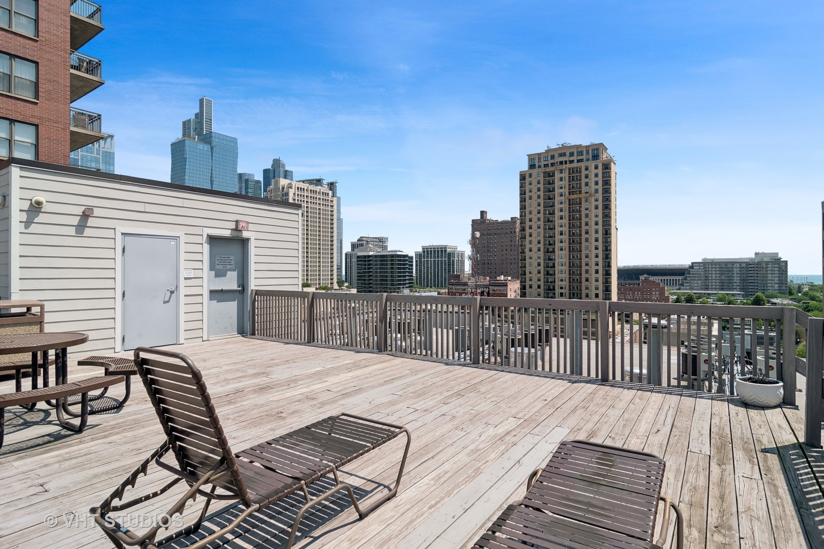 1503 South State Street, Unit 813 Chicago, IL 60605 - Photo 10 of 11 a view of a roof deck with table and chairs a barbeque with wooden floor and fence