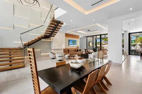 a large white kitchen with stainless steel appliances kitchen island granite countertop a refrigerator a stove and a sink with wooden floor