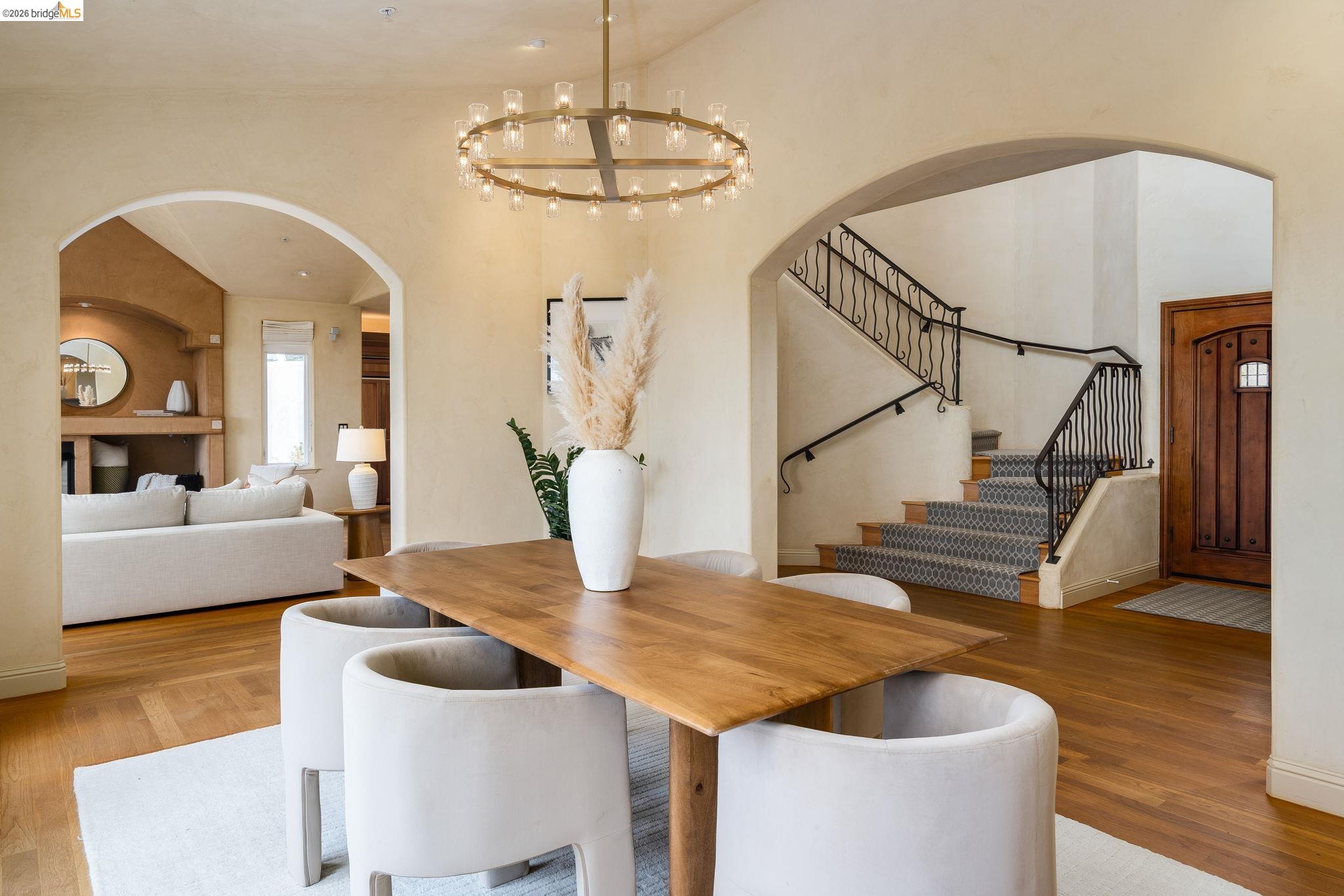 6257 Virgo Road Oakland, CA 94611 - Photo 19 of 60 Dining space with arched walkways, wood finished floors, stairway, a chandelier, and a high ceiling