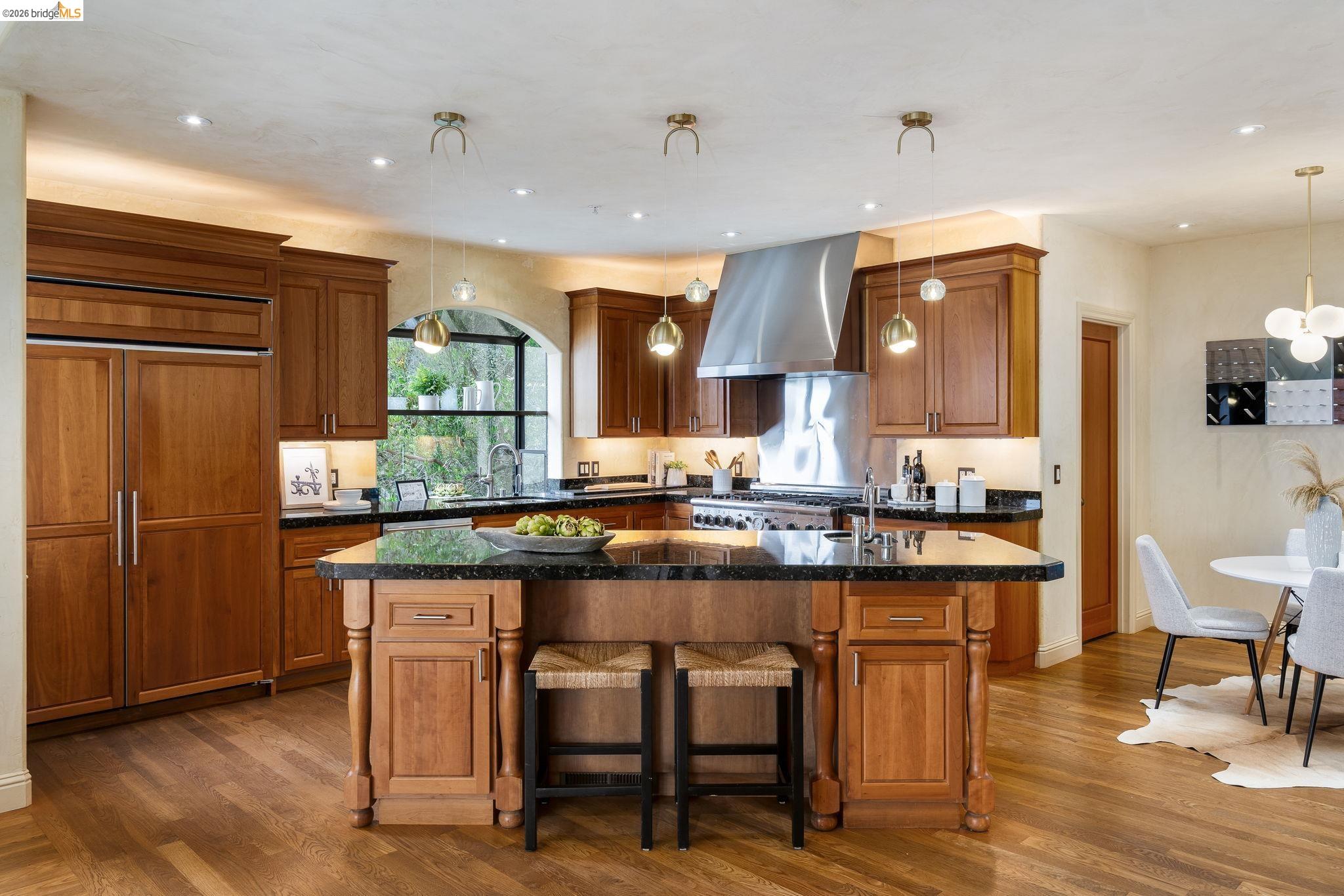 6257 Virgo Road Oakland, CA 94611 - Photo 24 of 60 Kitchen with a center island with sink, brown cabinets, hanging light fixtures, a breakfast bar, and dark wood finished floors