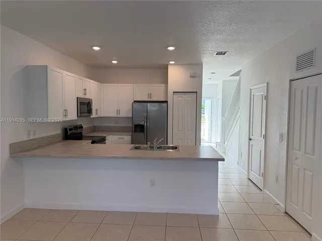a large kitchen with stainless steel appliances a refrigerator and a stove top oven