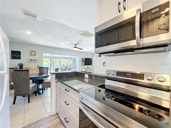 a kitchen with stainless steel appliances a stove a microwave and white cabinets