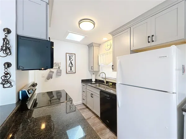 a kitchen with a refrigerator a sink dishwasher and white cabinets with wooden floor