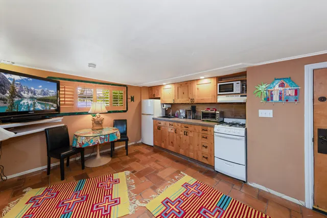 a kitchen with stainless steel appliances granite countertop a refrigerator a sink a stove and white cabinets with wooden floor