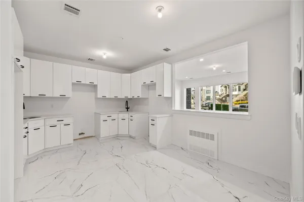 a kitchen with white cabinets and sink