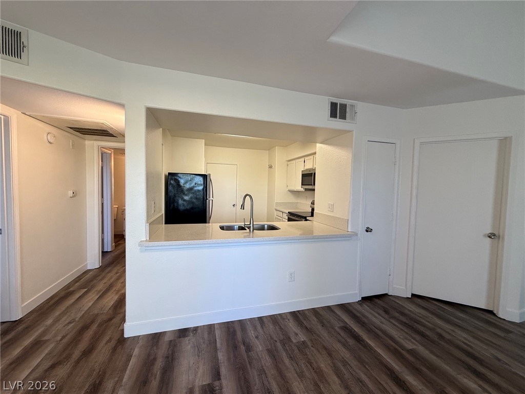 7255 West Sunset Road, Unit 2149 Las Vegas, NV 89113 - Photo 7 of 28 A contemporary open-concept kitchen features wood-look flooring and a functional breakfast bar.