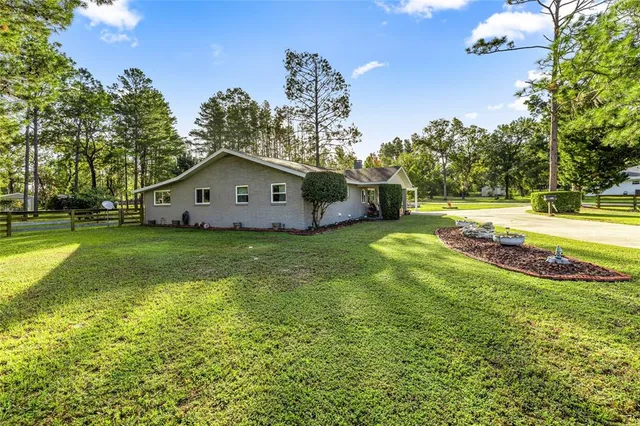 a view of a house with a big yard and large trees