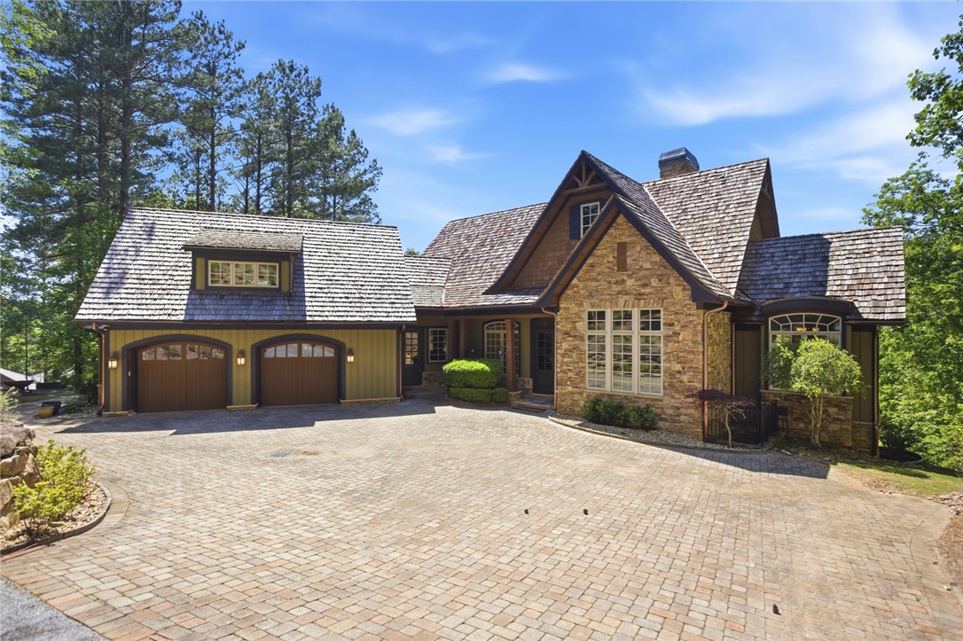 Crafted with stone and wood accents, this home features a large attached garage and a paver driveway.