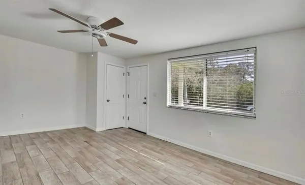 a view of empty room with wooden floor and fan