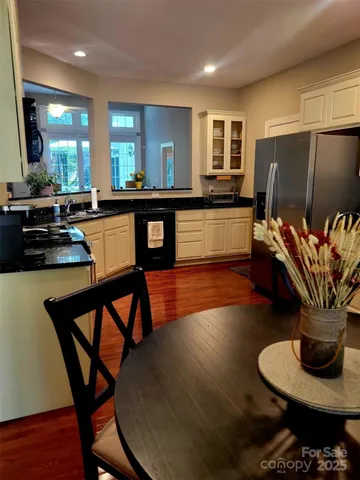 a kitchen with stainless steel appliances granite countertop wooden floor dining table and chairs
