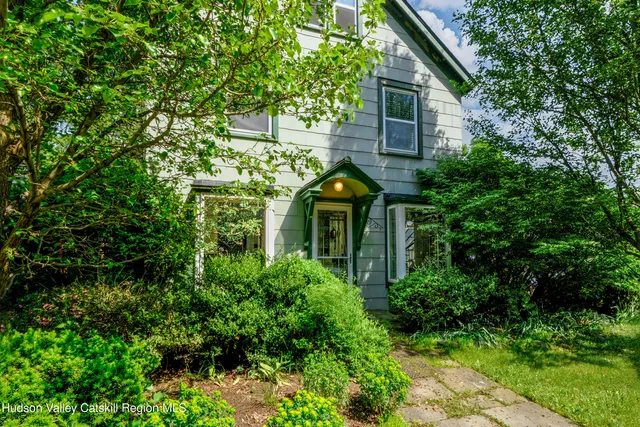 a view of a brick house with plants and large tree
