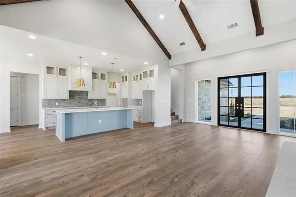 a large kitchen with stainless steel appliances granite countertop a large counter top a wooden floors and a large window