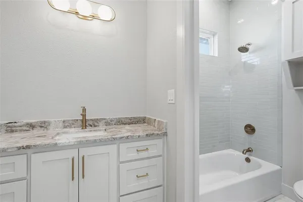 a bathroom with a granite countertop sink a mirror and a bathtub