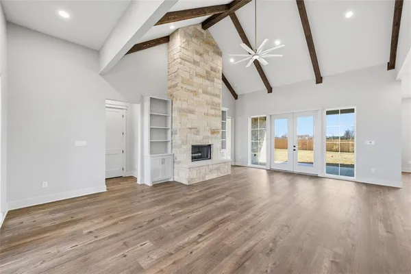 a view of an empty room with wooden floor and a fireplace