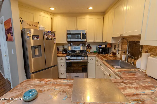 a kitchen with stainless steel appliances kitchen island granite countertop a sink a counter top space and cabinets