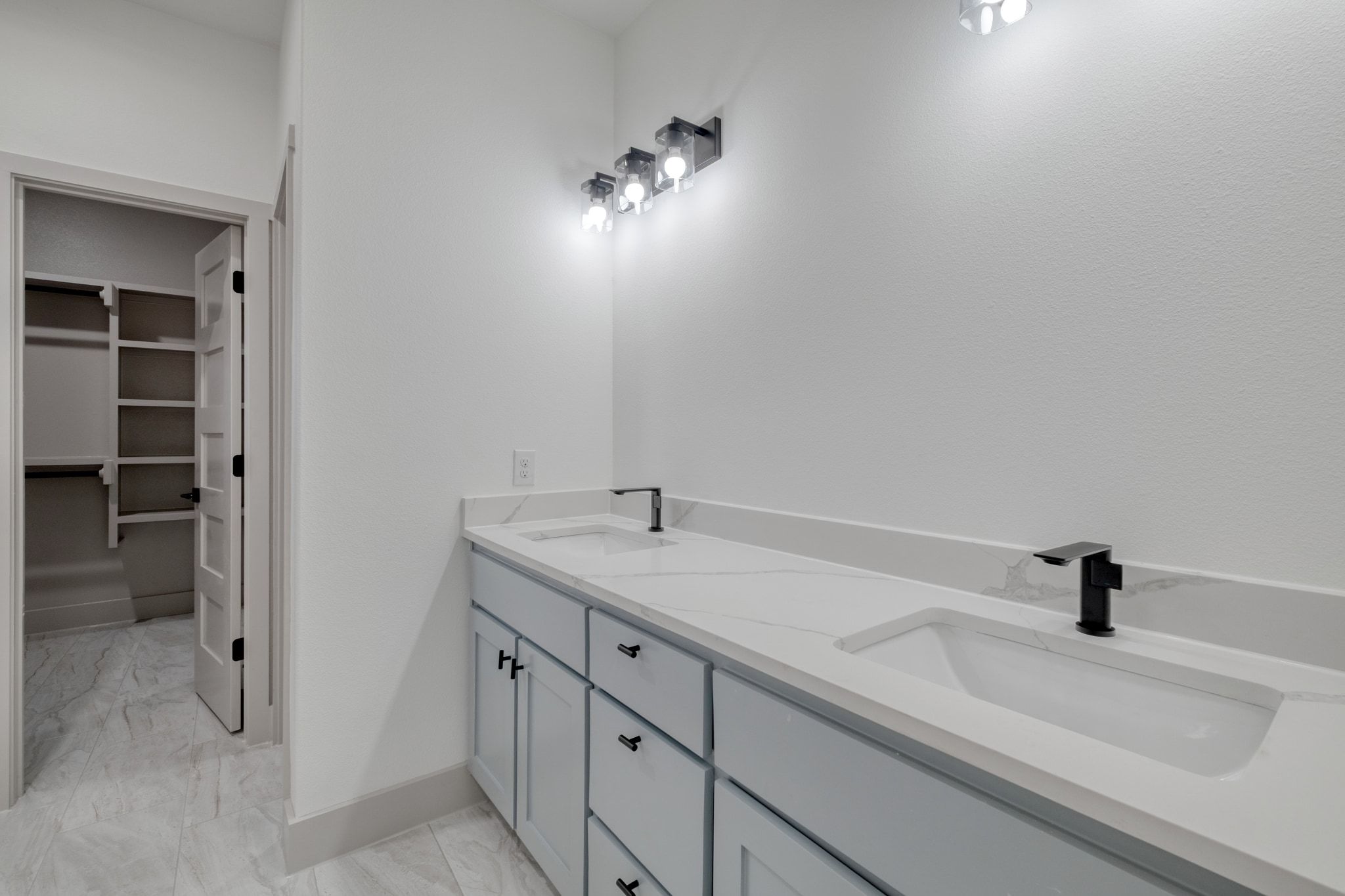 202 Washington Street Elgin, TX 78621 - Photo 14 of 26 Full primary bath featuring double vanity, light marble finish floors, and a walk in closet