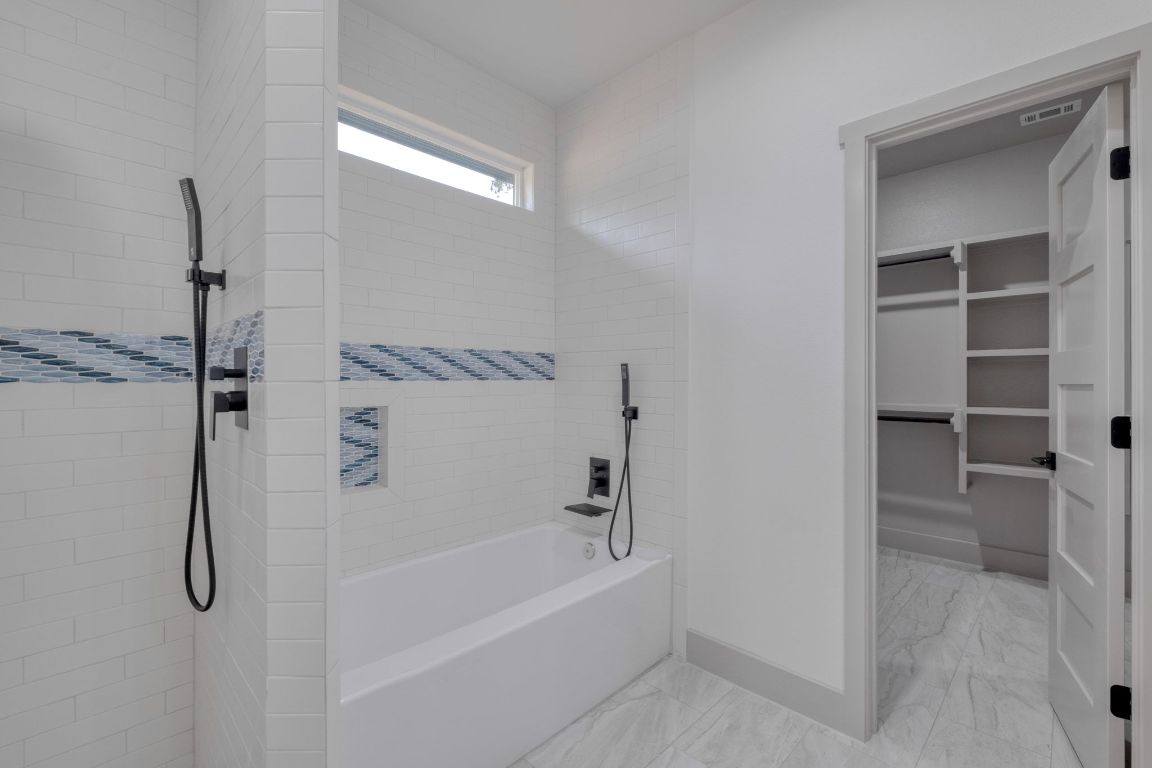 202 Washington Street Elgin, TX 78621 - Photo 15 of 26 Full bath featuring tiled shower, a garden tub, a walk in closet, and light marble finish flooring