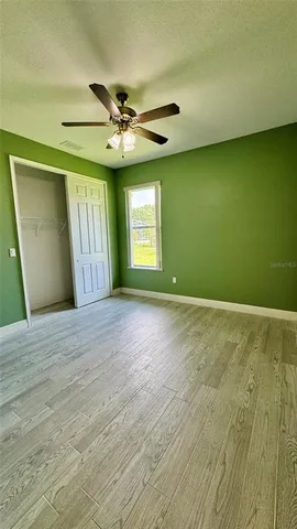 a view of an empty room with window and chandelier fan