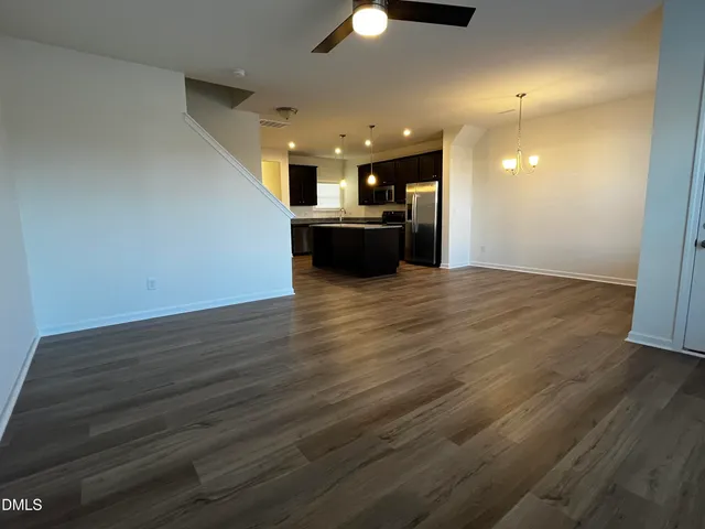 a view of kitchen and empty room with wooden floor