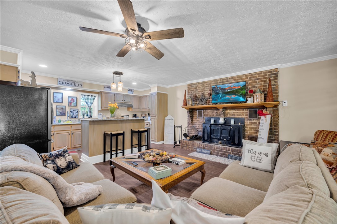3030 Smith McGee Road Iva, SC 29655 - Photo 10 of 46 An inviting open-concept living space features a cozy brick fireplace with a wood-burning stove and a breakfast bar for casual dining.
