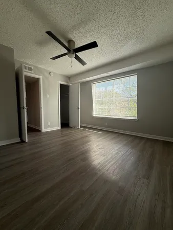 a view of an empty room with wooden floor and a window