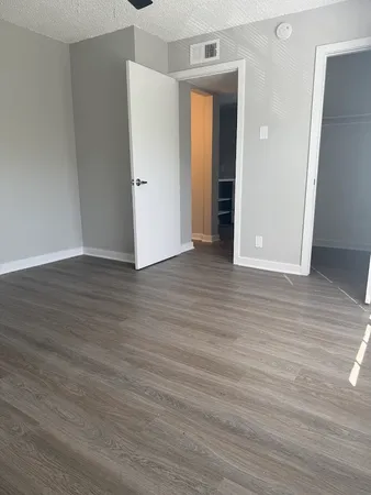a view of an empty room with wooden floor and closet