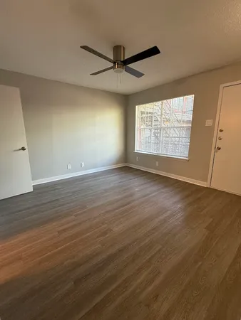a view of an empty room with wooden floor and a window