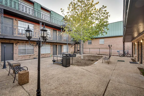 a view of a backyard with table and chairs potted plants and a large tree