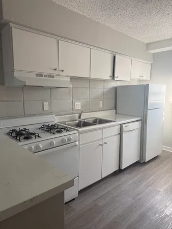 a kitchen with cabinets appliances and wooden floor
