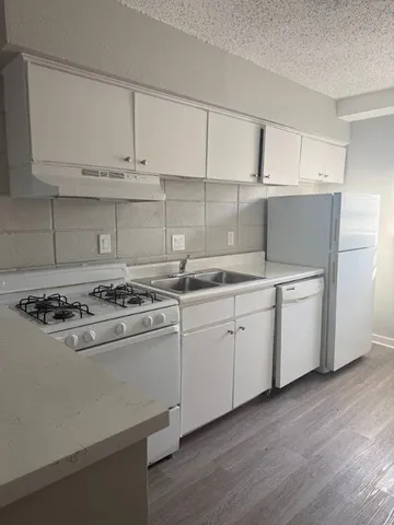 a kitchen with cabinets appliances and wooden floor