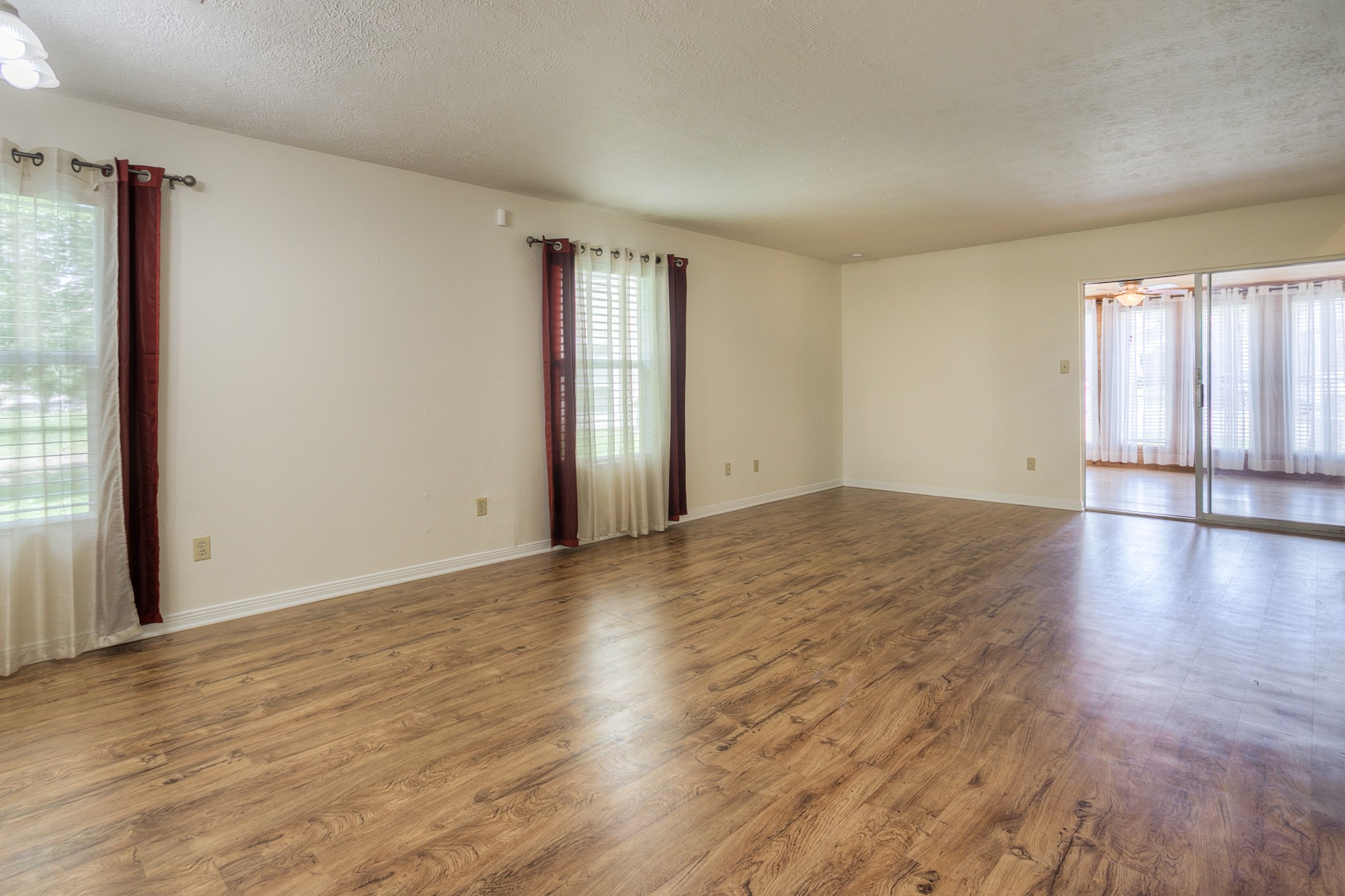 287 Broadmoor Street Trinity, TX 75862 - Photo 5 of 36 an empty room with wooden floor and windows with curtains view