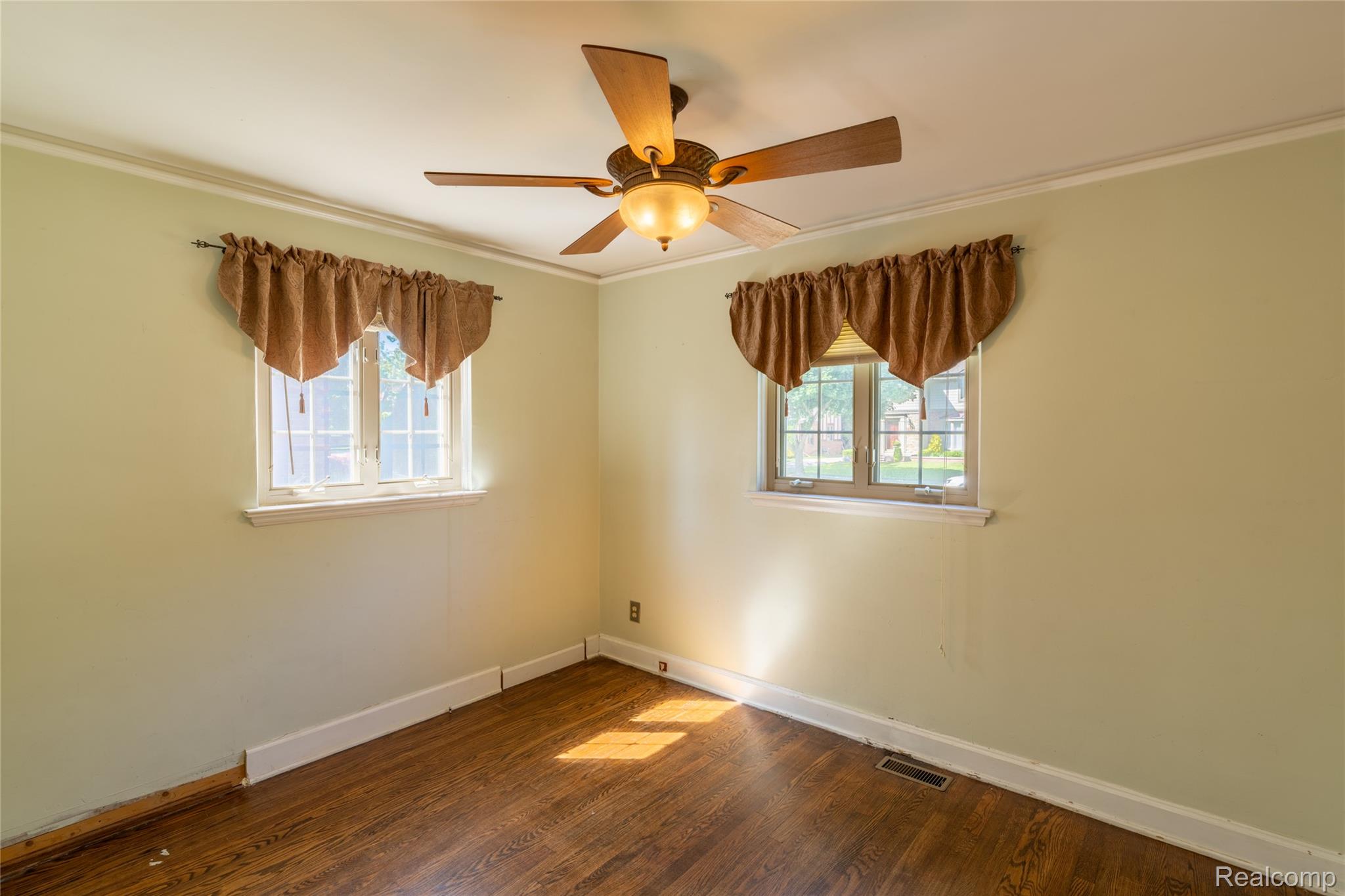 1481 Oxford Road Grosse Pointe, MI 48236 - Photo 26 of 29 Room featuring two large windows, wood-finish flooring, a ceiling fan with integrated lighting, and crown molding