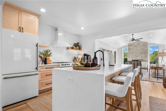 a kitchen with stainless steel appliances granite countertop a sink dishwasher a stove and a refrigerator with wooden floor